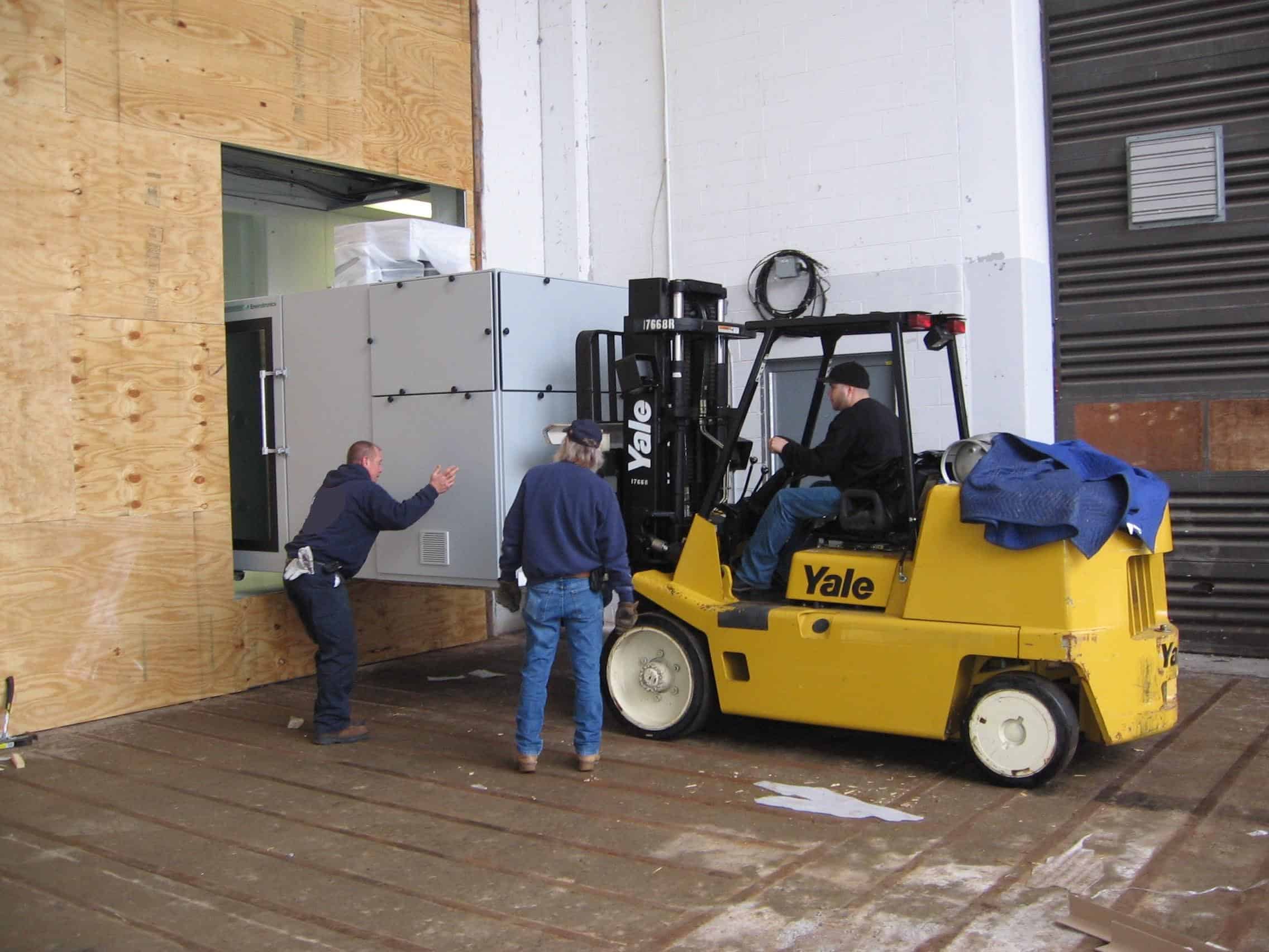 forklift moving large piece of equipment